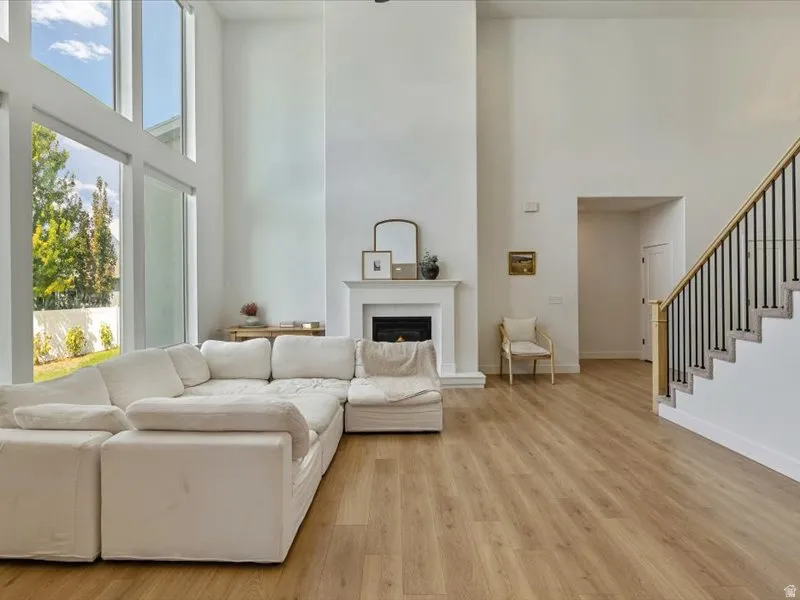 Two-story ceilings, fireplace with mantel, wood-finish flooring, and a staircase with an open railing