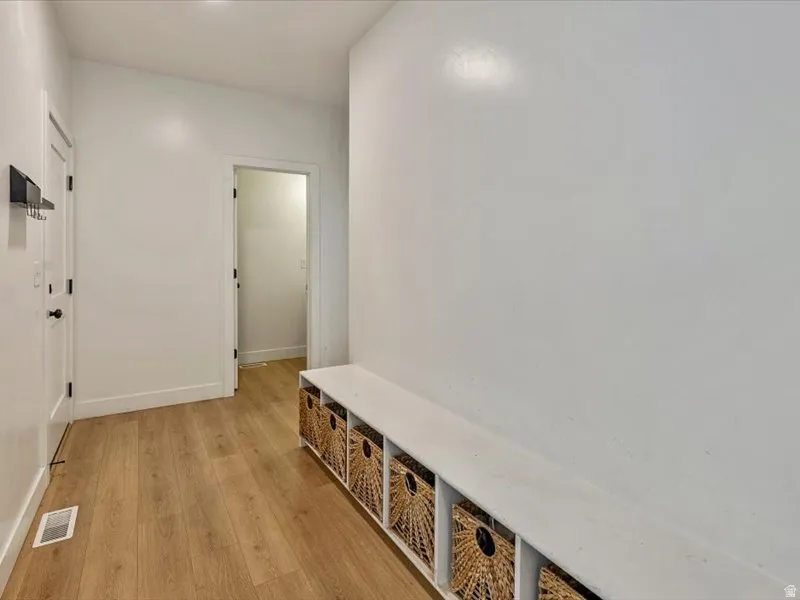 Wood-finish flooring, built-in storage bench, and white interior doors with matte black hardware