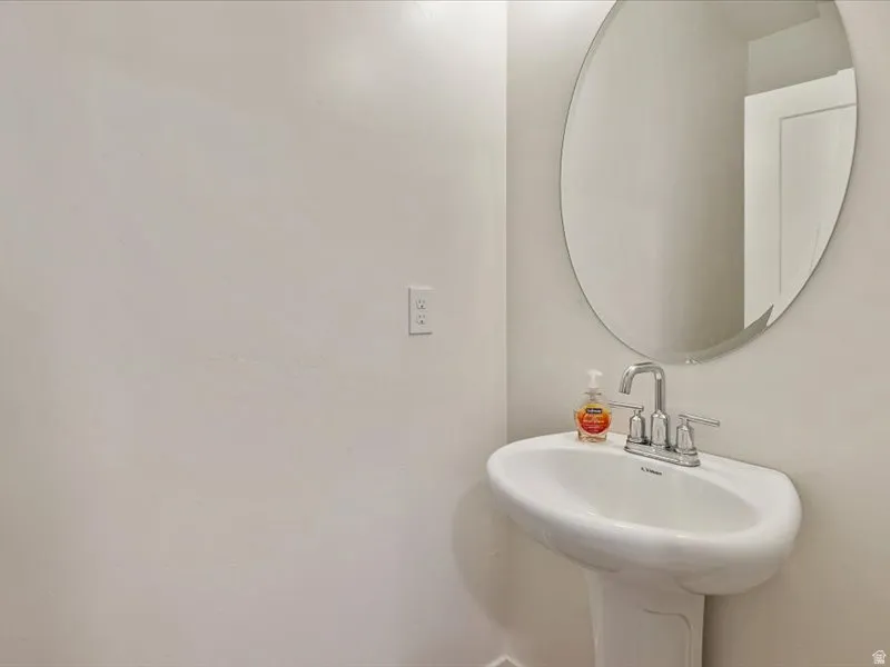 Pedestal sink with a chrome faucet and an oval mirror