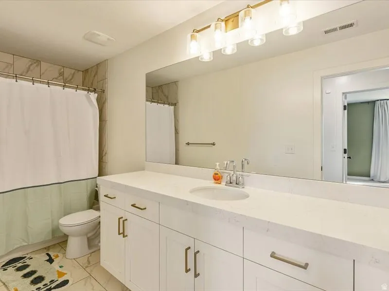 Extended vanity with integrated sink, white cabinetry, and brushed brass hardware