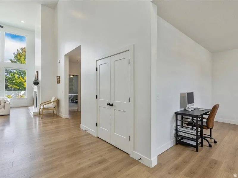 Wood-finish flooring throughout, bright white walls, and a recessed fireplace with a white mantel