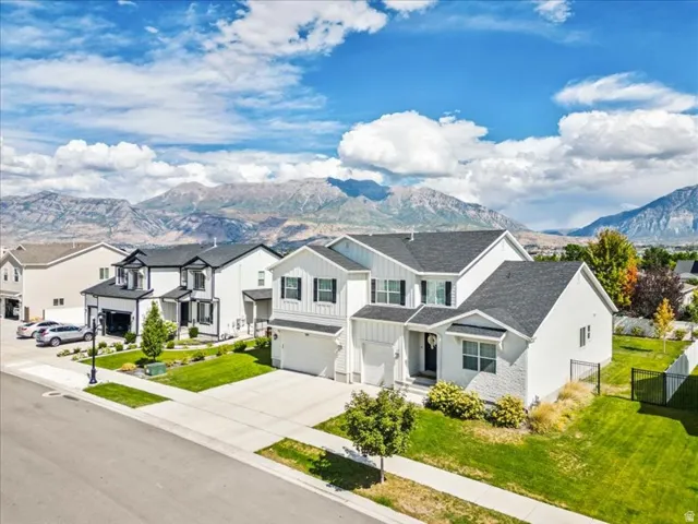 Modern two-story residence with a multi-gabled roof, attached two-car garage, and a manicured lawn