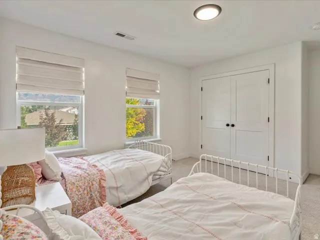 Dual windows with privacy blinds, recessed ceiling light, and white paneled bi-fold closet doors