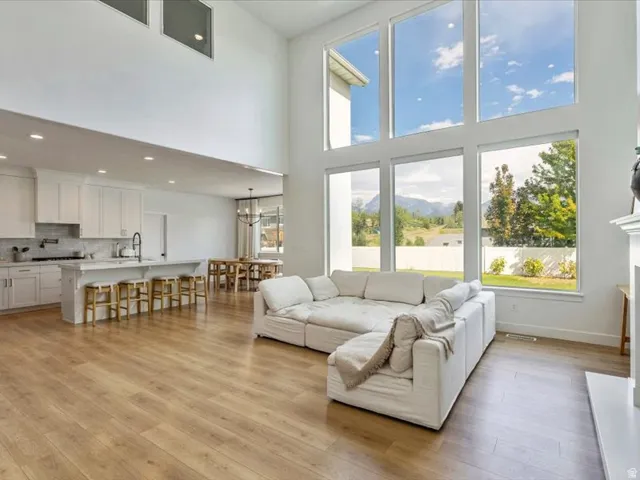 Two-story ceilings, expansive window wall, wood-finish flooring, island kitchen with white cabinetry, and a formal dining area