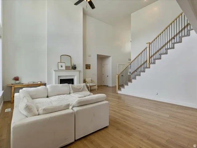 Vaulted ceilings, wood-finish flooring, staircase with metal balusters, and a fireplace with a white mantel