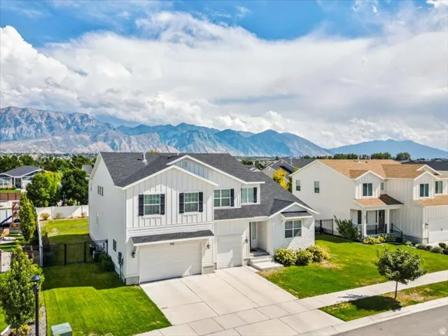 Two-story residence featuring white vertical siding, black-shutter windows, a two-car garage, and a concrete driveway