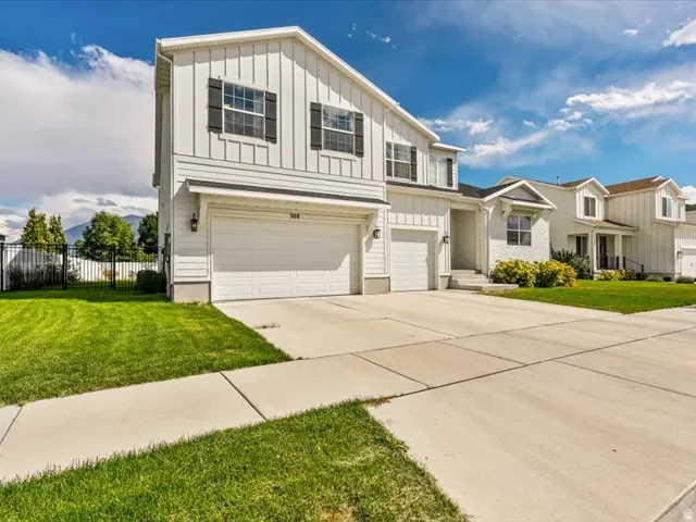 Two-story residence featuring white board and batten siding and a two-car garage