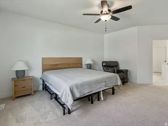 Vaulted ceiling with a ceiling fan, light-toned carpeting, and white wall finishes