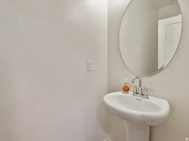 Pedestal sink with a chrome faucet and an oval mirror