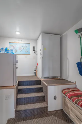 Carpeted stairs leading to an upper level, featuring recessed lighting, a built-in storage bench, and a built-in refrigeration platform