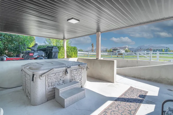 Covered patio with a mounted ceiling light, concrete flooring, and a hot tub