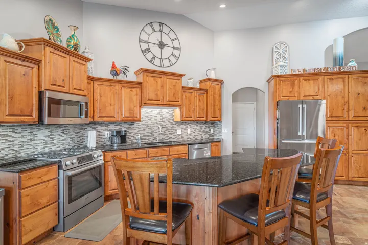 Kitchen featuring wood-finish cabinetry, stainless steel appliances, granite countertops, and a tile backsplash