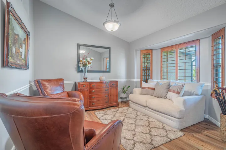 Wood-finish flooring with light gray wall paint, accented by a bay window with wood-framed panes, and a hanging pendant light fixture