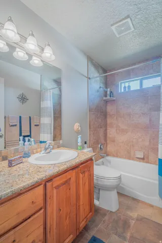 Warm wood-finish vanity with an integrated sink, complementing a stone-look countertop and backsplash