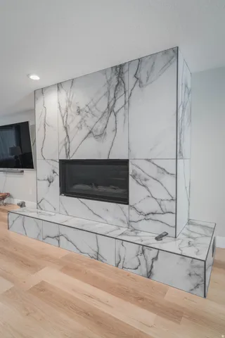 Modern fireplace with a marble-patterned surround, an integrated linear firebox, and a coordinated hearth