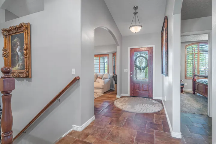 Wood-finish flooring in the entryway with a decorative front door featuring leaded glass