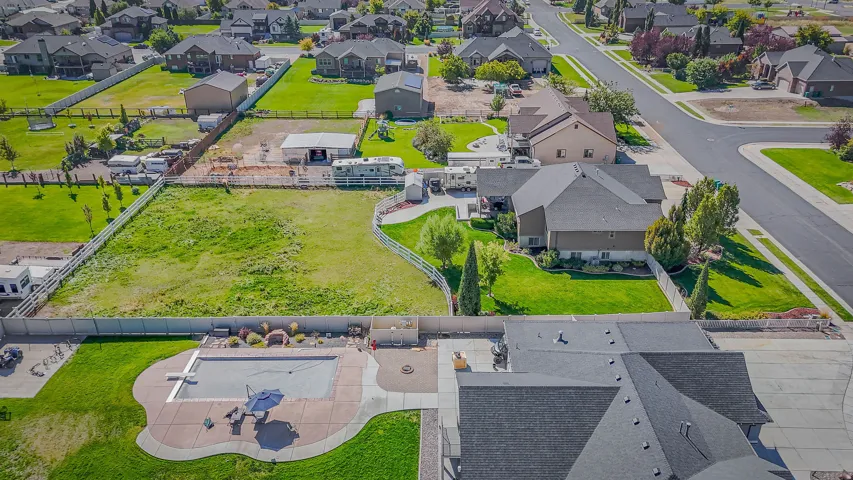 Expansive lot featuring a large in-ground swimming pool with surrounding concrete patio, a dedicated fire pit area, and extensive green space