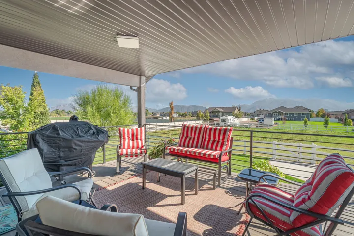 Covered outdoor deck with wood-finish flooring, black metal railing, and distant mountain scenery