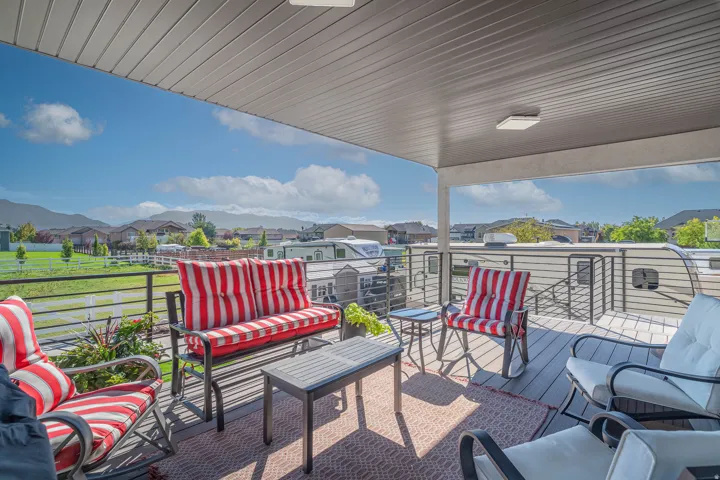 Covered outdoor deck with mountain scenery, featuring a horizontal metal railing and a wood-finish floor