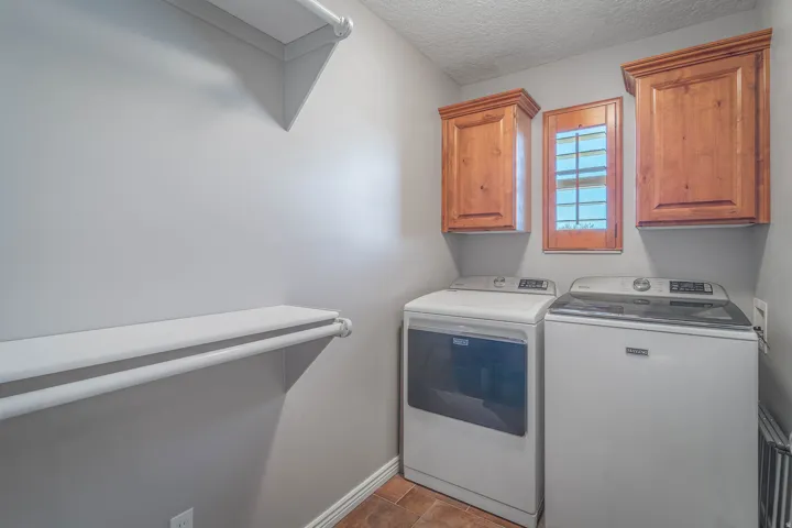 Window with wood frame, upper wood-finish cabinetry, built-in shelving, and tile flooring