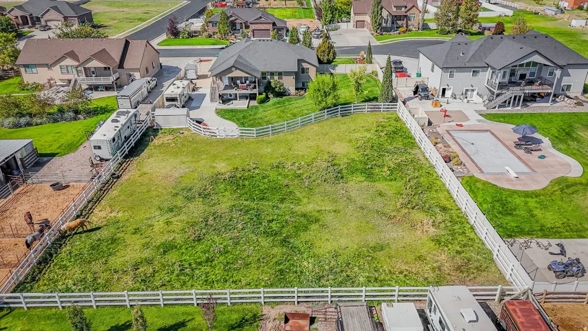 Expansive backyard featuring a manicured lawn, white fencing, and a dedicated animal enclosure