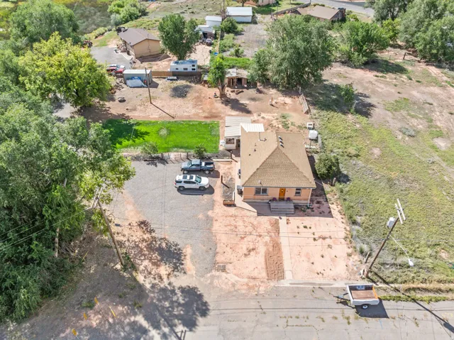 Gable roofline residence with a front entry, concrete driveway, and gravel parking area