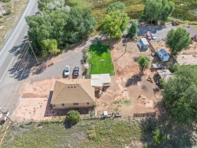 Expansive property featuring a main residence, additional structures, gravel parking areas, and mature trees