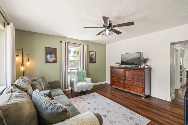 Hardwood flooring, painted walls, ceiling fan, and window with natural light