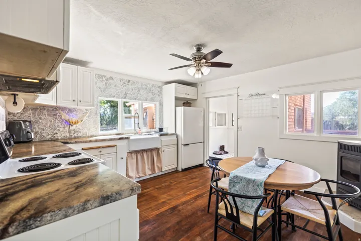 White cabinetry with integrated appliances, wood-finish flooring, and a ceiling fan