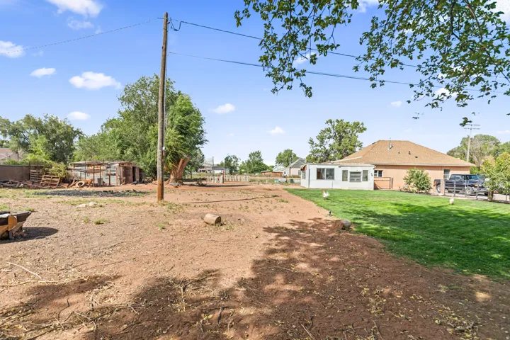Expansive outdoor area with a partially grassed lawn, a detached storage structure, and mature trees