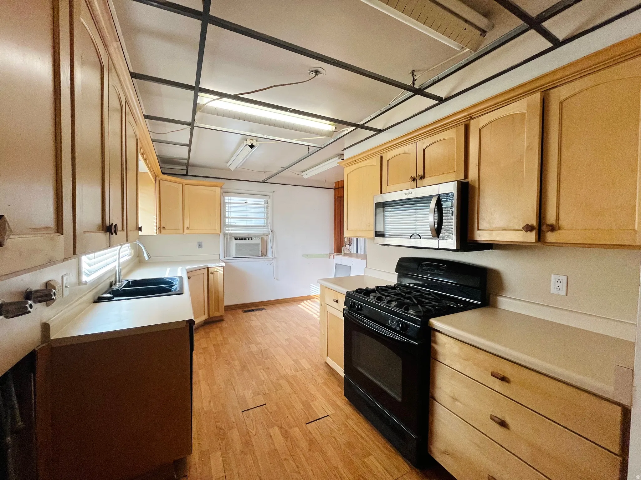 Kitchen with wood-finish cabinetry, light-toned countertops, and wood-finish flooring
