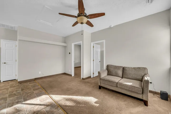 Recessed ceiling with a built-in ceiling fan, light-toned wall paint, and a combination of carpet and tile flooring
