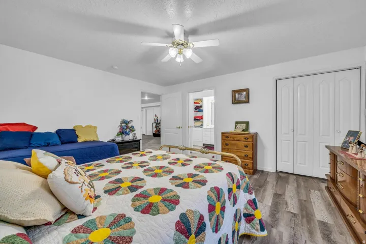 Wood-finish flooring, white bi-fold closet doors, and a ceiling fan with integrated lighting