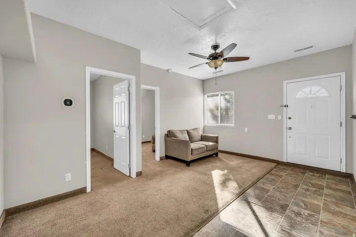 Entry area featuring patterned floor tile, a white entry door with an arched glass insert, and a ceiling fan with integrated lighting