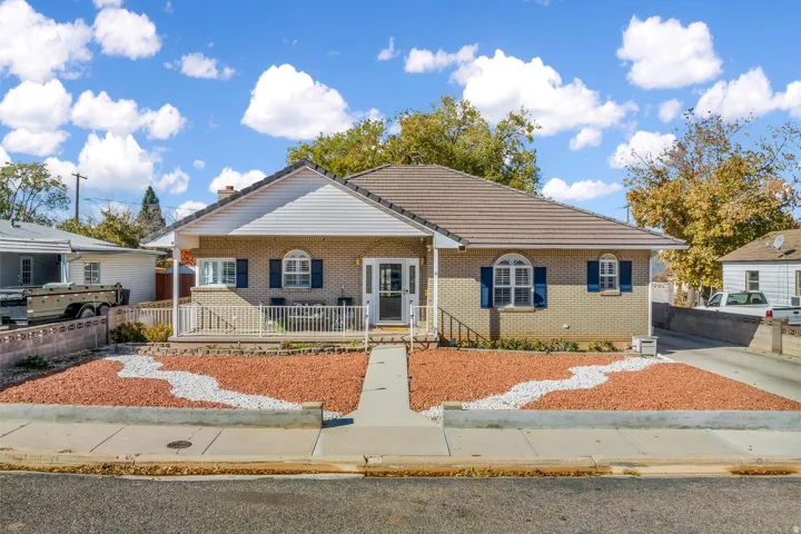 Brick exterior with a tiled roof, covered front porch, and front yard with decorative rock landscaping