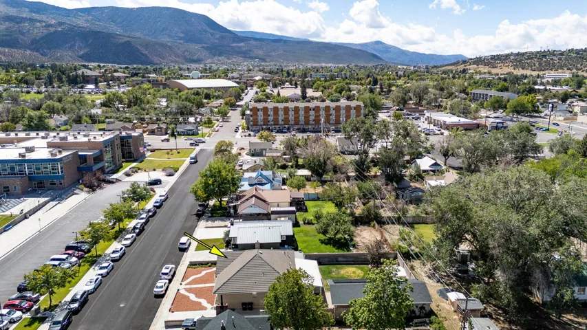 Mountain backdrop with a residential street, commercial structures, and mature trees