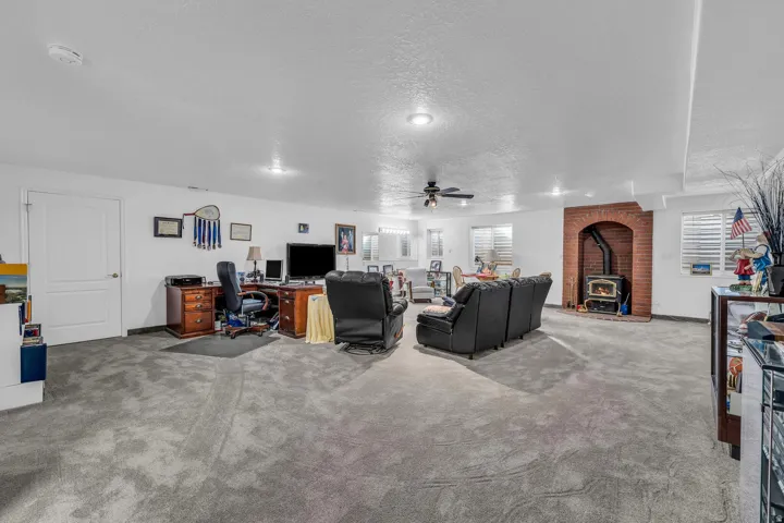 Spacious room featuring carpeting, recessed lighting, a ceiling fan, and a brick-arch fireplace with an insert