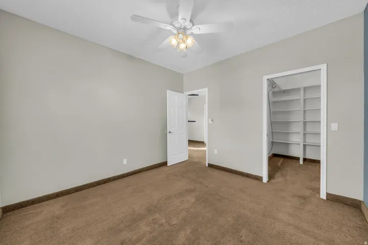Carpeted flooring, light gray wall paint, and a ceiling fan with integrated lighting