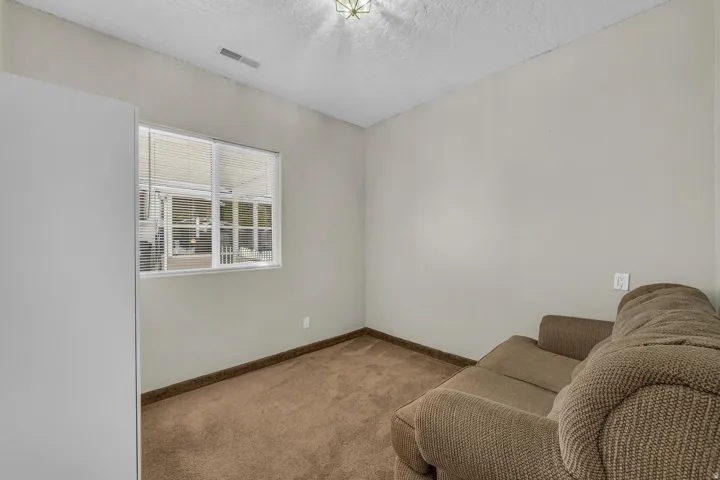Neutral wall color, carpeted flooring, and a single window with blinds