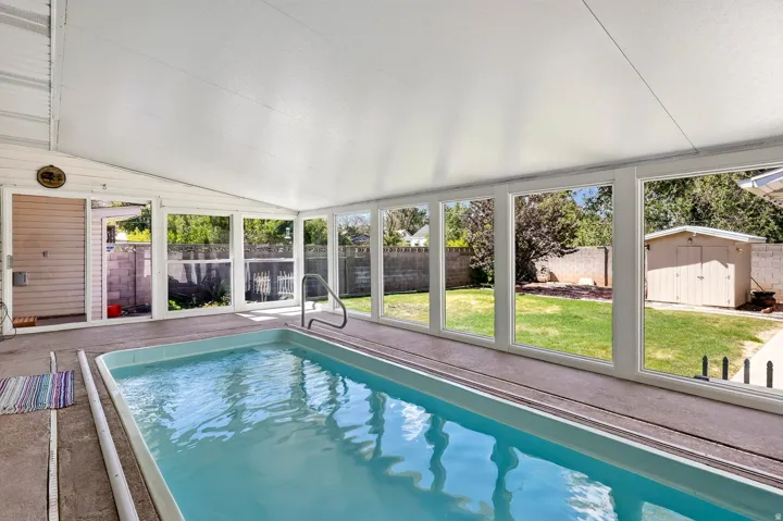 Enclosed swimming pool with full-height windows, a white ceiling, and a light blue pool finish