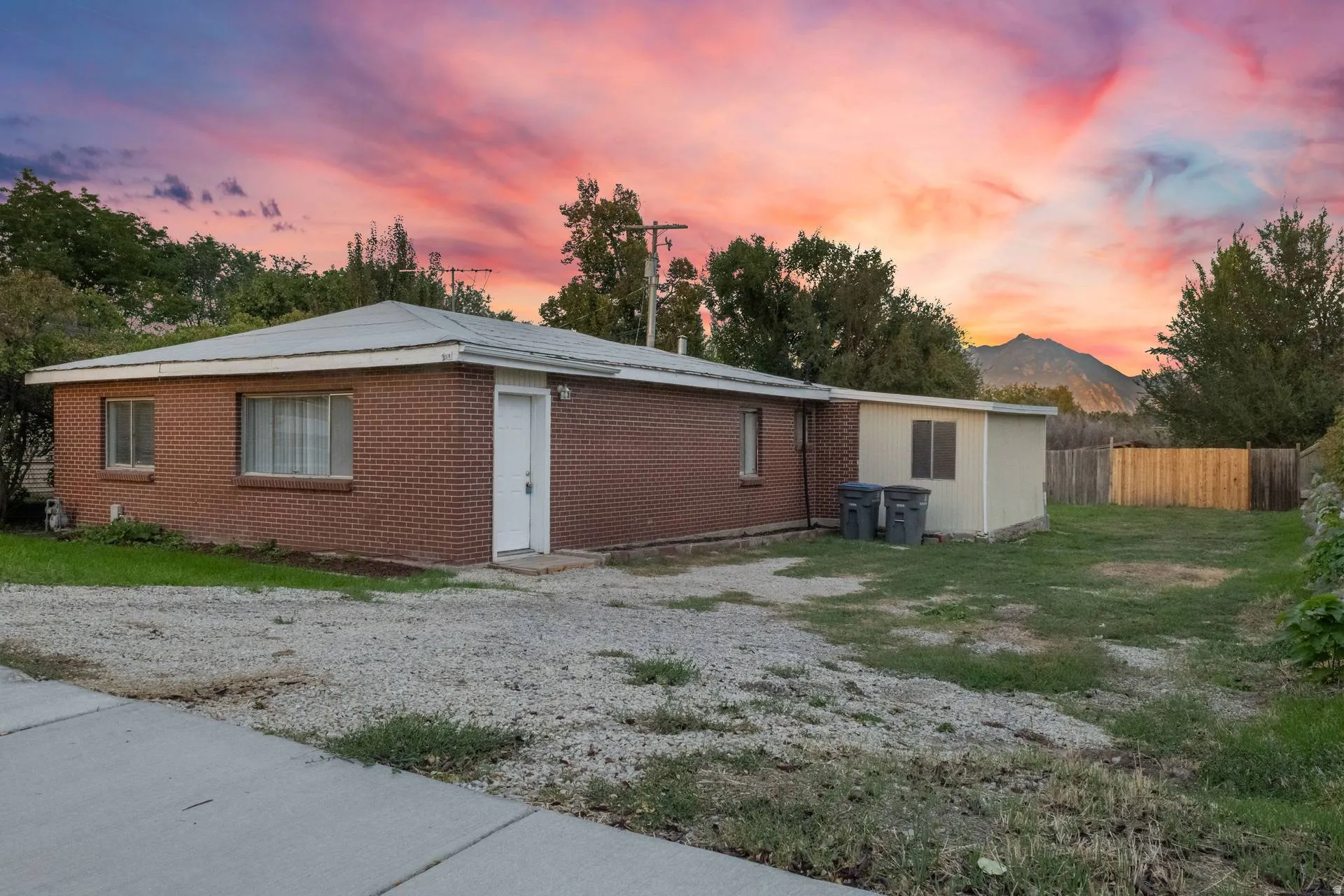 Brick exterior with white trim, a gravel driveway, an expansive backyard, and a detached shed