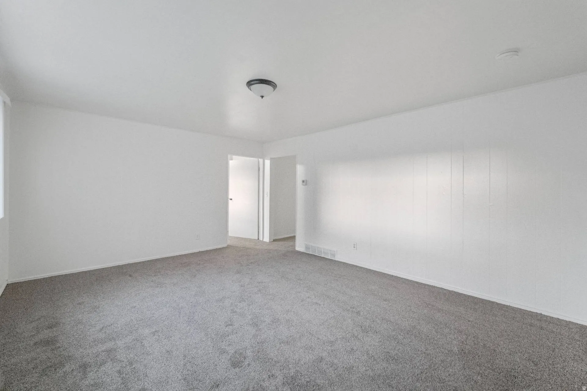 Carpeted flooring with white wall paneling, flush mount ceiling light, and white interior doors