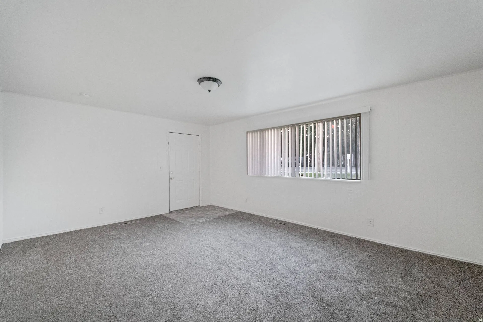 Neutral white wall finishes, gray carpet flooring, recessed lighting, and a window with vertical blinds