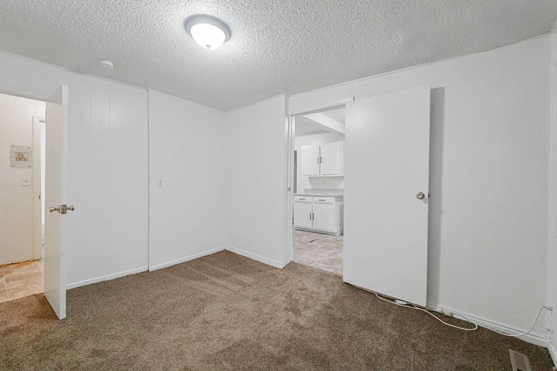 Carpeted flooring with white painted walls and ceiling-mounted lighting