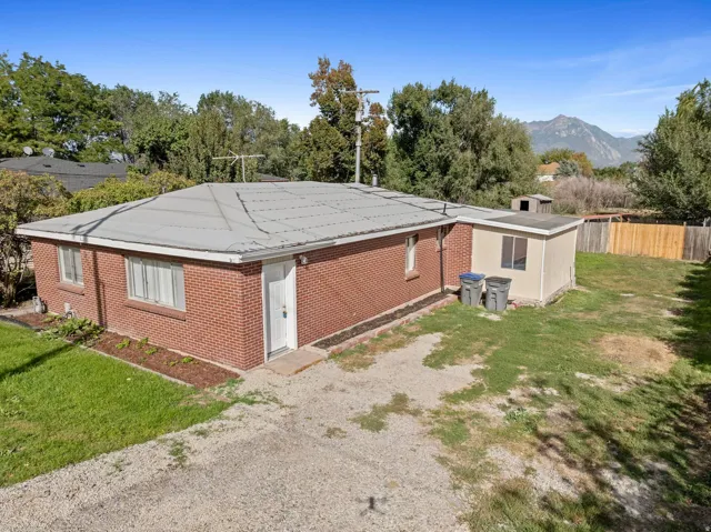 Red brick exterior with white trim, a gravel driveway, a separate detached structure, and a fenced backyard