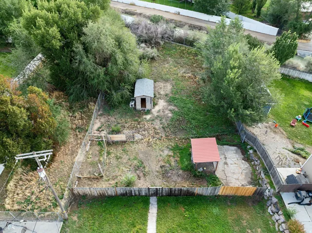 Fenced yard with mature trees, a storage shed, and an additional covered structure