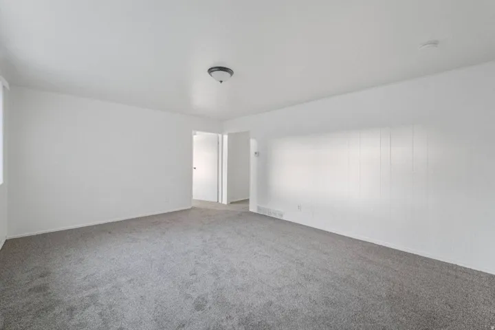 Carpeted flooring with white wall paneling, flush mount ceiling light, and white interior doors