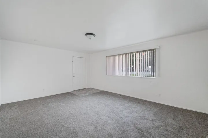Neutral white wall finishes, gray carpet flooring, recessed lighting, and a window with vertical blinds