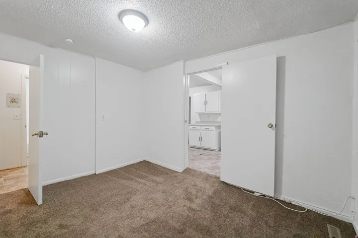 Carpeted flooring with white painted walls and ceiling-mounted lighting