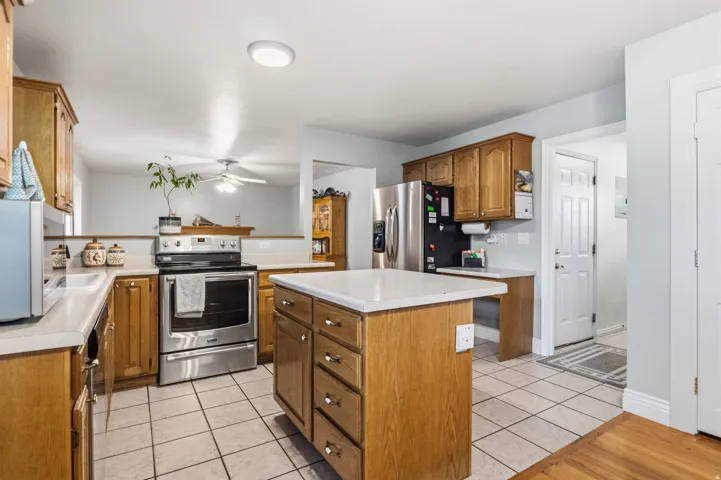 Kitchen featuring wood cabinetry, stainless steel appliances, a center island with countertop, and tile flooring